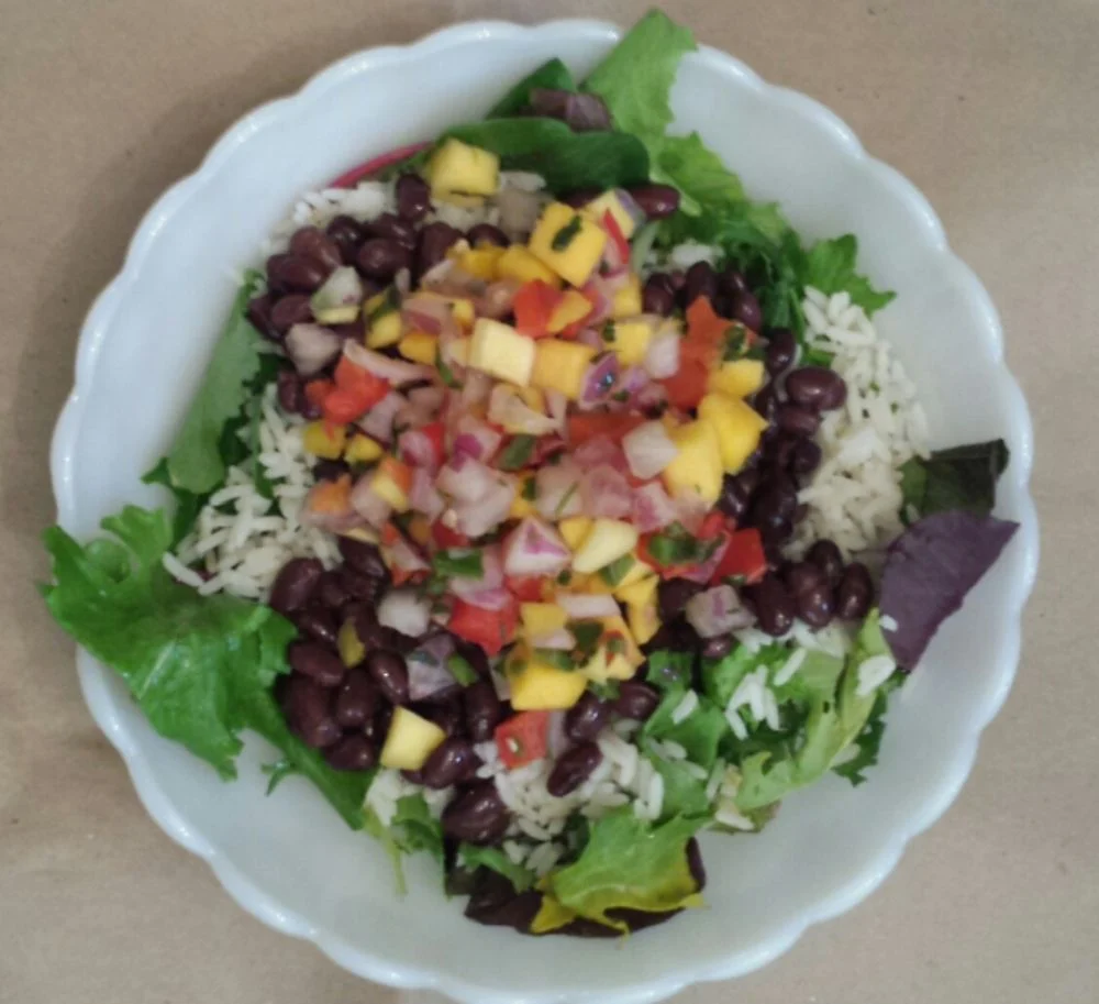 Zesty Mango, Black Bean, and Rice Salad with fresh greens, black beans, cooked rice, and mango salsa.